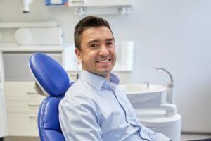 Man smiling in dental chair awaiting a dental extraction