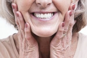 Woman clutching jaw after receiving implant supported dentures