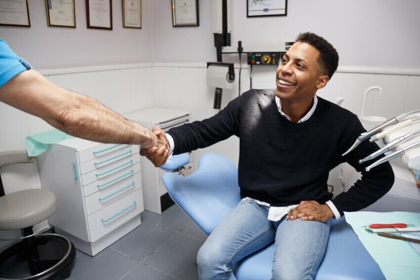 Young man in black shirt shaking hands with dentist