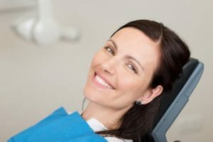 Young woman sitting in dental chair smiling after receiving root canal