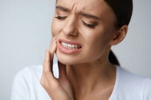 Woman clutching her mouth in pain, needing emergency dentistry